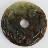 A Chinese carved dark spinach/celadon Jade disc, Ming style but likely Qing, 6.5cm diameter.