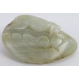 A Chinese carved celadon and russet Jade boulder, in the form of a fish, pebble and water foliage,