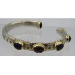 A heavy bespoke handmade silver bangle set in yellow metal, three cabochon garnets & three