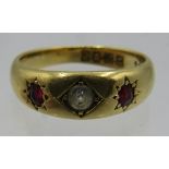 An 18ct yellow gold ring set with centre white stone and two rubies, size L. Approx weight 4.6