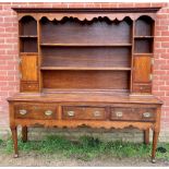 A good 18th century oak Welsh dresser, the top section with dentil cornice and shaped canopy,