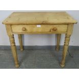 An antique stripped pine side table, housing one long drawer with turned wooden handles, on tapering