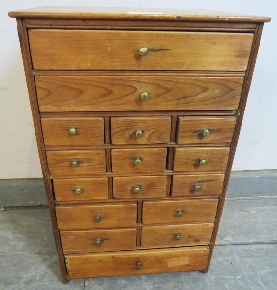 A diminutive antique pine tabletop collector’s cabinet, housing an array of 16 long and short