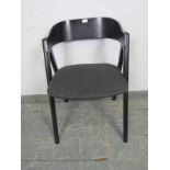 A contemporary ebonised desk chair with curved back seat pad upholstered in dark grey, on canted