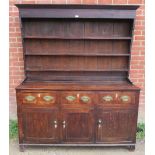 An 18th century oak Welsh dresser with three open shelves over a dresser base housing three short