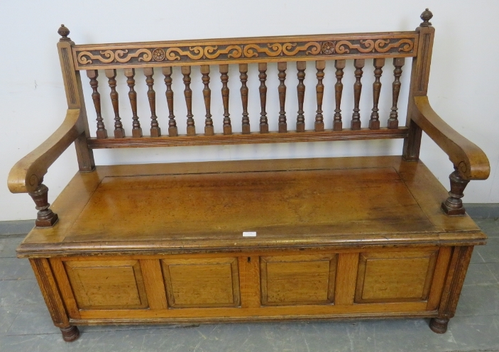 An Arts & Crafts walnut settle by James Shoolbred, with turned ball finials, carved frieze and