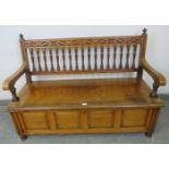 An Arts & Crafts walnut settle by James Shoolbred, with turned ball finials, carved frieze and