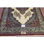 A Persian rug with a central motif, on cream ground and a blue wide border with signature, see