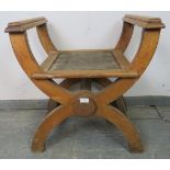 An Arts & Crafts limed oak ‘X-frame’ stool with armrests, on curved supports with side stretchers.