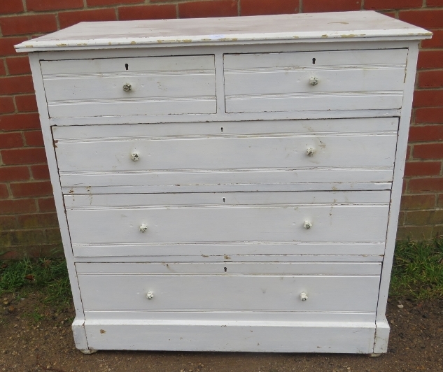 An antique pine chest of two short over three long graduated drawers painted distressed white, on