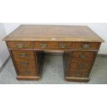 An Edwardian oak pedestal desk, with inset brown leather writing surface, housing a configuration of