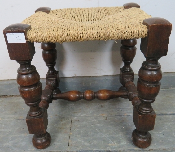 A small vintage oak stool with braided rope seat, on cup and cover supports united by a turned and