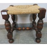 A small vintage oak stool with braided rope seat, on cup and cover supports united by a turned and