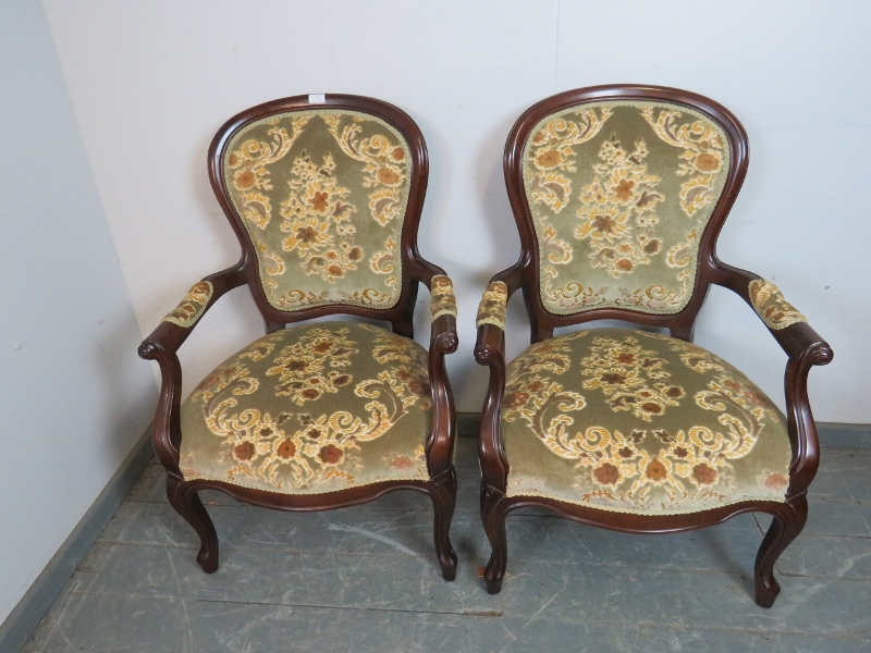 A pair of antique style mahogany open-sided armchairs, upholstered in a textured patterned material,