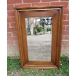 A rectangular bevelled rectangular wall mirror in a heave medium oak frame. H92cm W61cm D5cm (