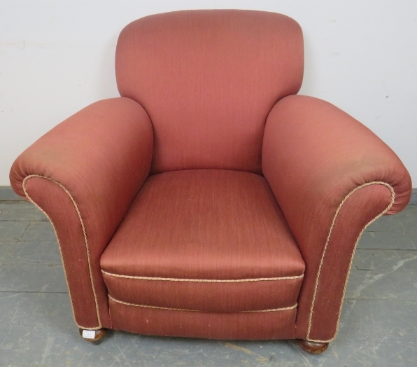 An Edwardian club armchair, re-upholstered in light burgundy material with silver braided rope trim,