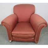 An Edwardian club armchair, re-upholstered in light burgundy material with silver braided rope trim,