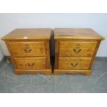 Two reproduction light oak bedside chests, each housing two drawers with fancy swan-neck handles, on