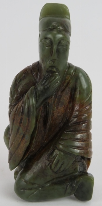 A Chinese carved dark spinach Jade crouching Sage, holding his beard in a ponderous pose, with