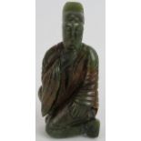 A Chinese carved dark spinach Jade crouching Sage, holding his beard in a ponderous pose, with