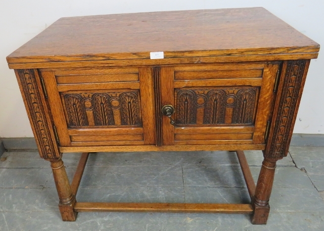 A reproduction medium oak side cabinet, with relief carving in the 17th century taste, on tapering