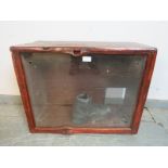 A vintage glazed display cabinet with naturalistic wood surround, currently containing an old