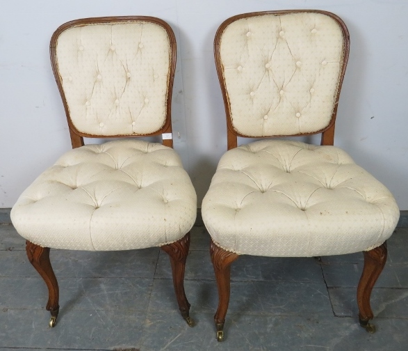 A pair of antique French oak occasional chairs, upholstered in buttoned cream material, on