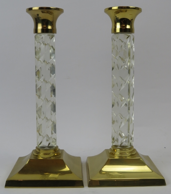 A pair of Waterford crystal candlesticks, 20th century. Faceted glass stems with brass sconces and