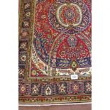 A good Persian Tabriz carpet central cartouche on a red ground with flowers and a deep patterned