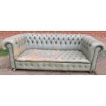 A vintage three-seater Chesterfield sofa, upholstered in distressed grey leather with brass studs,