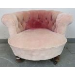 A turn of the century low bedroom tub chair, upholstered in antique buttoned velvet, on turned