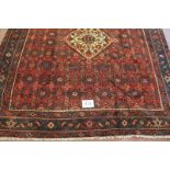 A fine Persian Hamadan carpet central cream motif on a heavy patterned red ground. Good colour and
