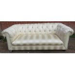 A vintage three-seater chesterfield sofa, reupholstered in striped cream damask material, on ball