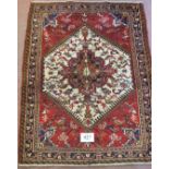 A Persian Heriz rug, with a cream hexagonal central panel on a red ground. 168cm x 110cm (approx).