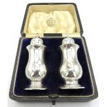 A pair of silver pepper pots on pedestal feet, Birmingham 1911, cased. Approx 3"/8cm, approx