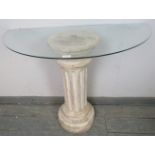 A glass topped demi-lune console table, raised on a Corinthian style column base. H72cm W100cm D51cm
