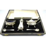 A three piece silver condiment set on pad feet, Birmingham 1969, with silver salt and mustard spoon,