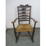 A 19th century elm Lancashire ladderback rocking chair, with rush seat, on turned supports with