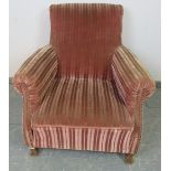An antique French club armchair upholstered in brown striped velveteen material with brass studs, on