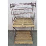 A pair of French large capacity steel wine racks painted claret red, on plywood bases with