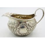 A small silver cream jug with 1/2 fluting and embossed decoration, silver marks worn. Approx