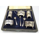 A five piece silver condiment set with pierced & swan decoration with two silver salt spoons and a