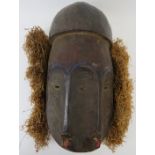 Tribal Art: An African Janus mask, Lega People, Congo. Carved and painted wood with a straw
