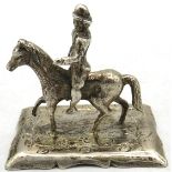 A white metal figure of a man riding a horse, marks to base, possibly Dutch. Approx 2"/5cm high