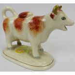 A late Victorian ceramic Ayrshire cow creamer. Hand painted with gilt highlights and supported on an