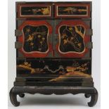 A Japanese lacquered miniature cabinet on stand, Meiji/Taisho period. The hinged doors opening to