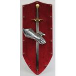 A sword and gauntlet mounted on a studded red velvet shield, 20th century. 40.1 in (103 cm)