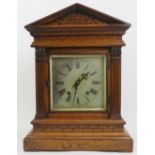 An oak cased Palladian style mantel clock, late 19th/early 20th century. With a bevelled glass front