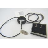 A black shark skin necklet with a large white metal pendant set with many precious & semi precious