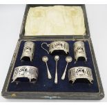 A five piece silver condiment set with pierced & swan decoration with two silver salt spoons and a